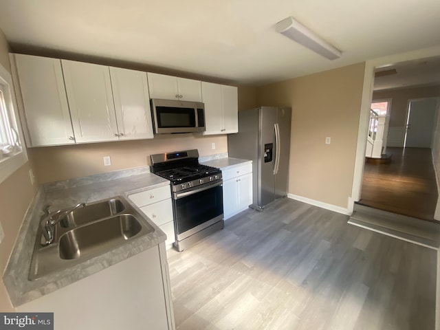 kitchen featuring white cabinets, sink, light wood-type flooring, and appliances with stainless steel finishes