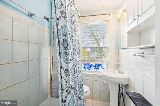 bathroom with tile patterned floors, toilet, tile walls, and sink