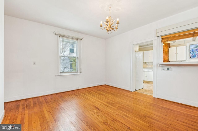 empty room featuring a chandelier and light hardwood / wood-style flooring