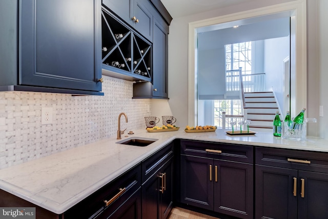 bar with decorative backsplash, a wealth of natural light, sink, and light stone countertops