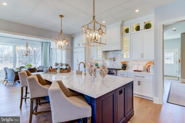 kitchen featuring white cabinetry, a wealth of natural light, light hardwood / wood-style floors, and hanging light fixtures