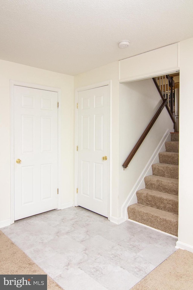 carpeted foyer entrance featuring a textured ceiling