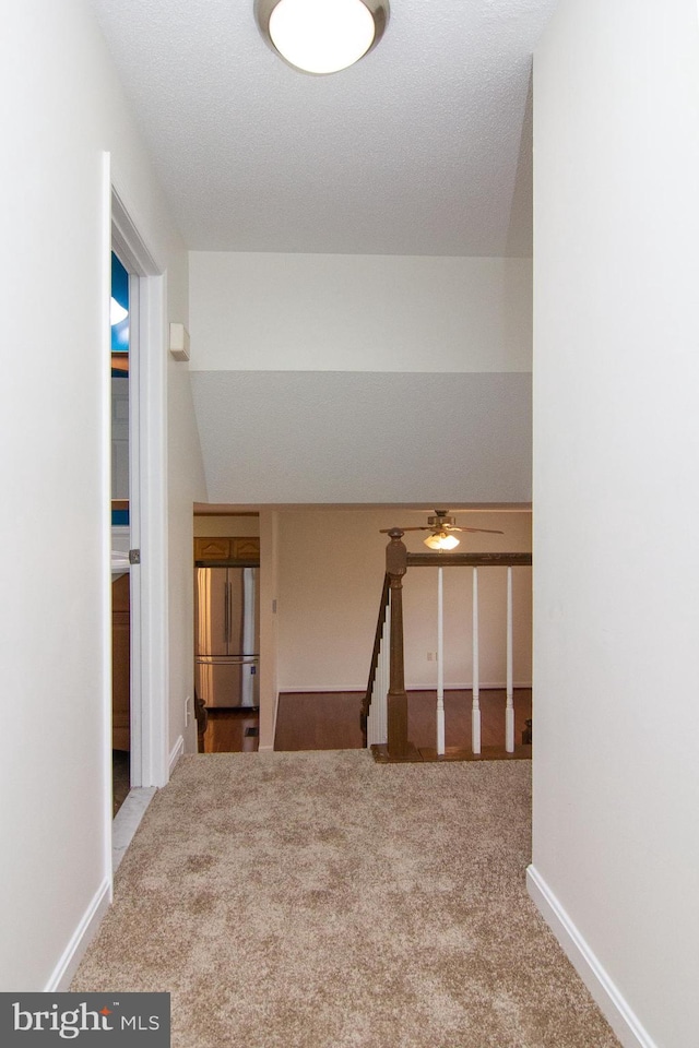 hallway featuring a textured ceiling and carpet flooring