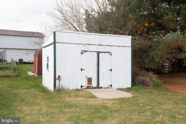 view of outdoor structure with a lawn and central AC