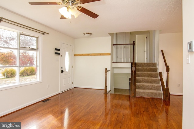 foyer entrance with wood-type flooring, ceiling fan, and a textured ceiling