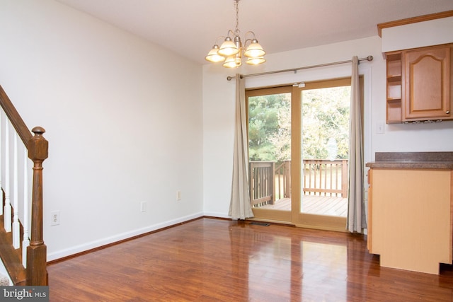 unfurnished dining area featuring dark hardwood / wood-style flooring and an inviting chandelier