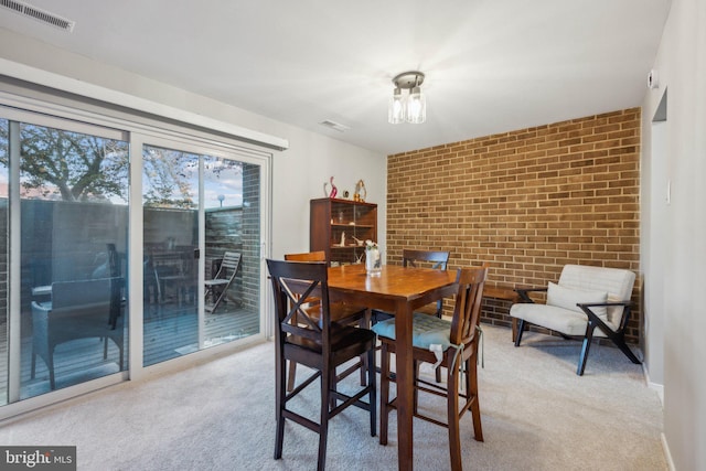 carpeted dining area featuring brick wall