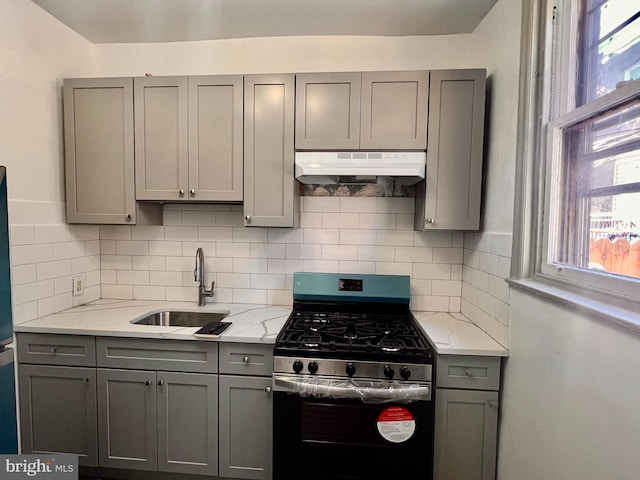 kitchen featuring gray cabinets, sink, stainless steel gas stove, and light stone counters