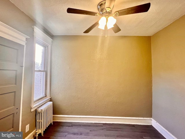 spare room with dark wood-type flooring, ceiling fan, a textured ceiling, and radiator heating unit