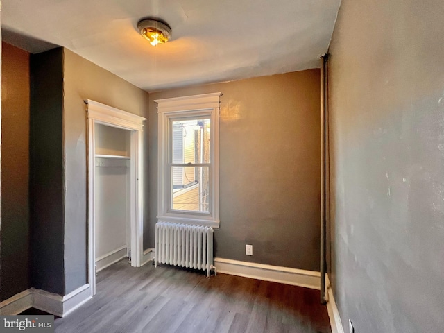 unfurnished bedroom with hardwood / wood-style floors, a closet, and radiator