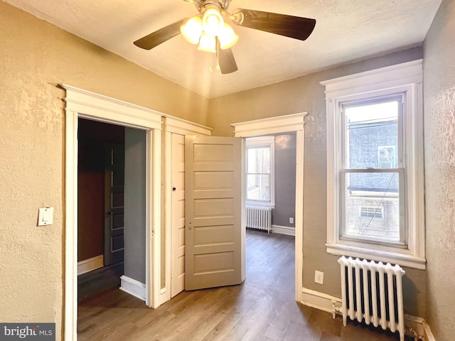 interior space featuring wood-type flooring, multiple windows, and radiator heating unit