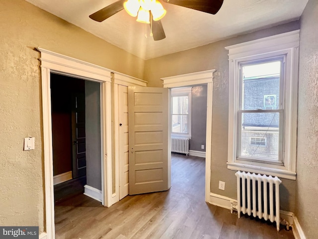 interior space with hardwood / wood-style flooring, ceiling fan, and radiator heating unit