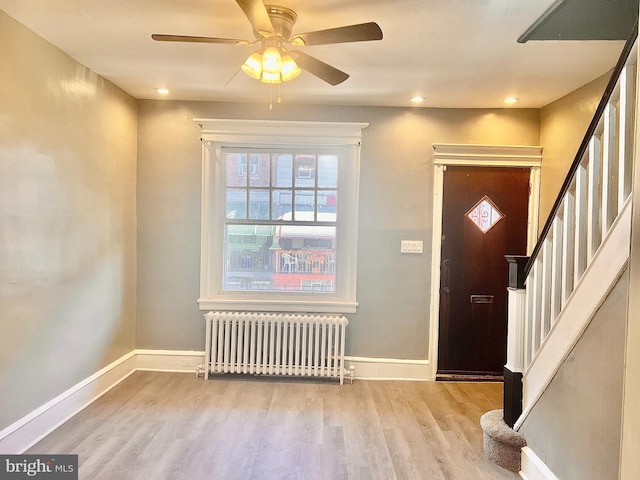 foyer featuring light wood-type flooring, ceiling fan, and radiator