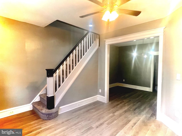 stairs with hardwood / wood-style flooring and ceiling fan