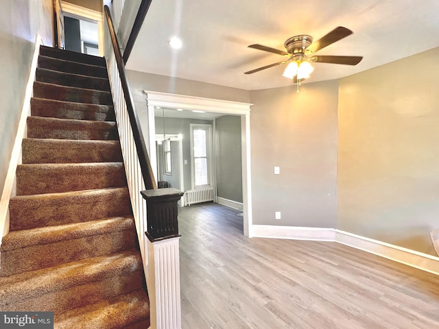 stairway featuring radiator heating unit, hardwood / wood-style flooring, and ceiling fan