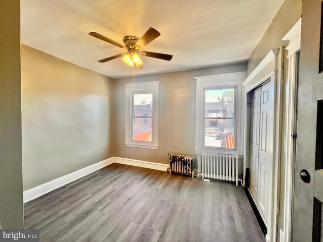 spare room with ceiling fan, radiator, and wood-type flooring