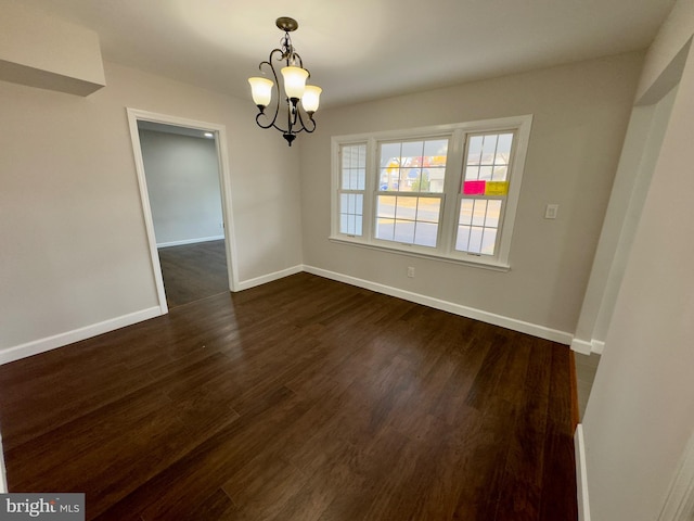 spare room with dark wood-type flooring and a chandelier