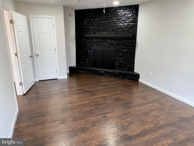 unfurnished living room featuring dark hardwood / wood-style floors and a large fireplace