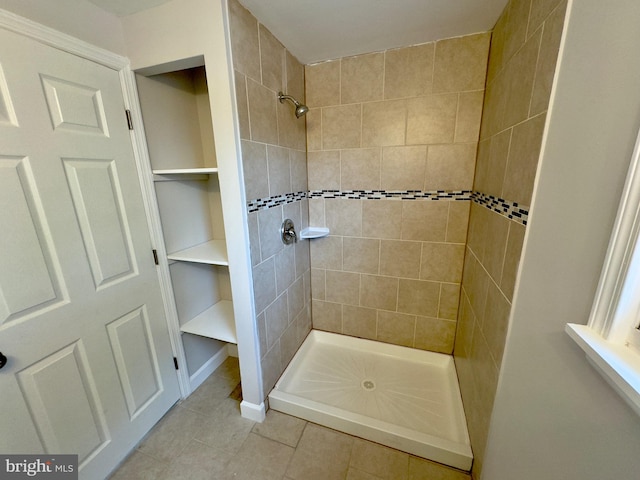 bathroom featuring tiled shower and tile patterned flooring