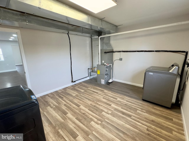 clothes washing area featuring heating unit and light wood-type flooring