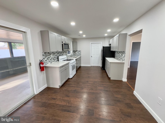 kitchen featuring black fridge, dark hardwood / wood-style flooring, gray cabinets, decorative backsplash, and white gas range oven