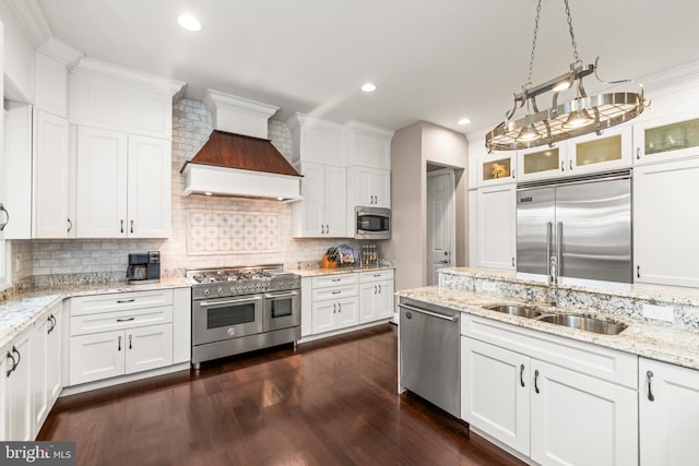 kitchen featuring built in appliances, white cabinetry, and decorative light fixtures