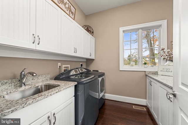 clothes washing area with independent washer and dryer, dark wood-type flooring, cabinets, and sink