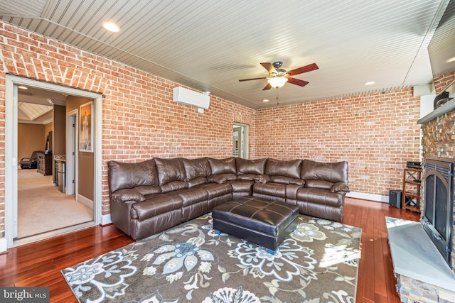 living room with dark hardwood / wood-style flooring, a fireplace, ceiling fan, and brick wall