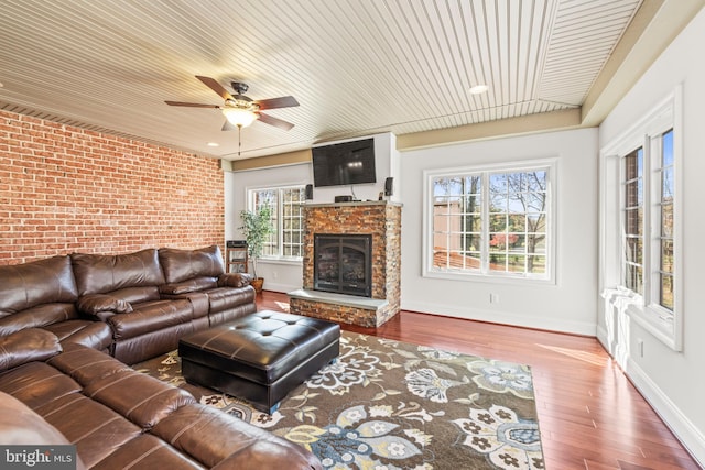 living room with hardwood / wood-style floors, a wealth of natural light, brick wall, and ceiling fan