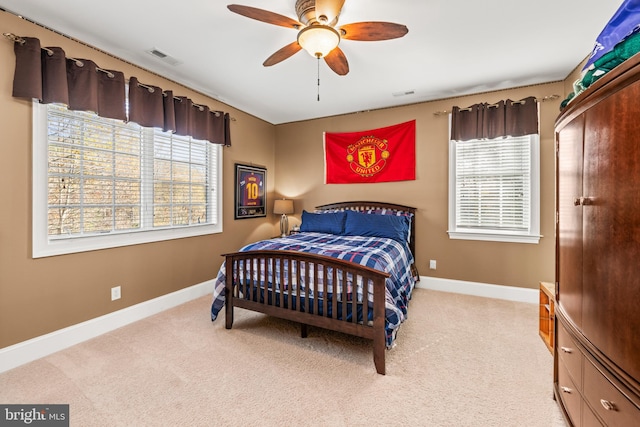 carpeted bedroom with ceiling fan and multiple windows