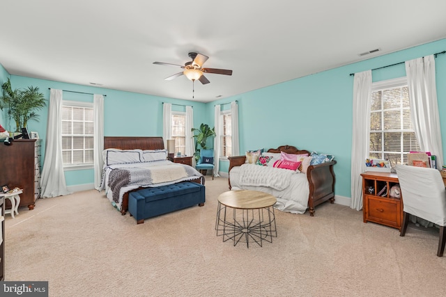 bedroom featuring ceiling fan, multiple windows, and light carpet