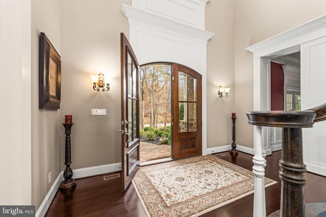 foyer featuring french doors, crown molding, dark hardwood / wood-style floors, and a towering ceiling