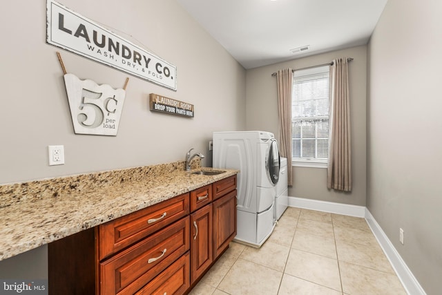 washroom featuring washing machine and dryer, cabinets, sink, and light tile patterned flooring