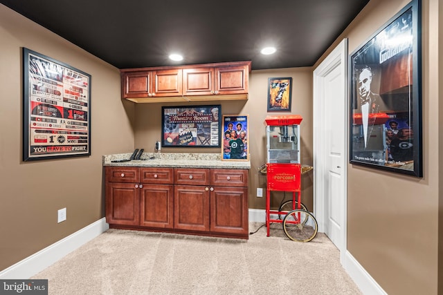 bar featuring light stone countertops and light colored carpet