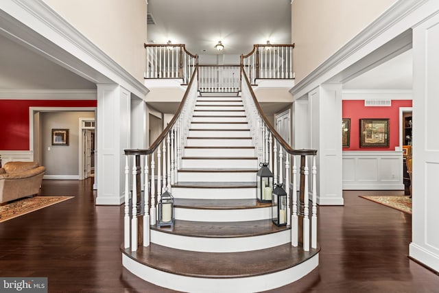 stairway featuring hardwood / wood-style flooring, ornate columns, and crown molding