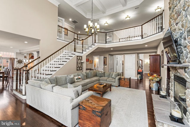 living room featuring a fireplace, a chandelier, dark hardwood / wood-style floors, and a towering ceiling