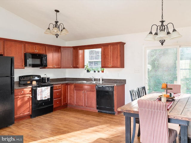 kitchen with light hardwood / wood-style flooring, a chandelier, lofted ceiling, decorative light fixtures, and black appliances