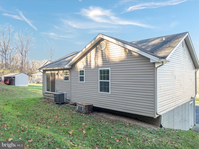 back of property featuring a lawn, cooling unit, and a shed