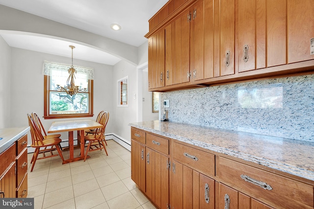 kitchen featuring tasteful backsplash, light stone counters, light tile patterned flooring, a notable chandelier, and pendant lighting