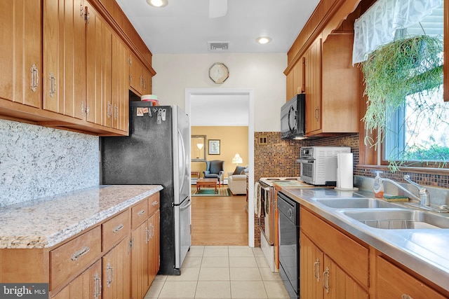 kitchen featuring black appliances, backsplash, sink, and light tile patterned floors