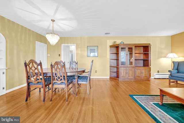 dining room with baseboard heating, light hardwood / wood-style floors, and an inviting chandelier