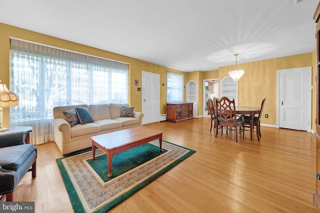 living room with an inviting chandelier, hardwood / wood-style floors, and a baseboard radiator