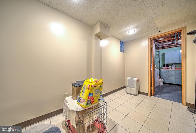 interior space with a paneled ceiling and light tile patterned floors