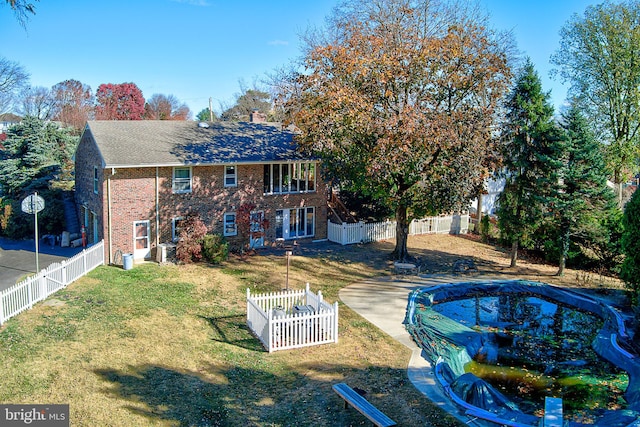 rear view of house with a lawn and a covered pool