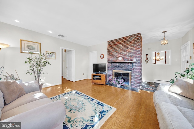 living room with a fireplace, a baseboard radiator, and wood-type flooring