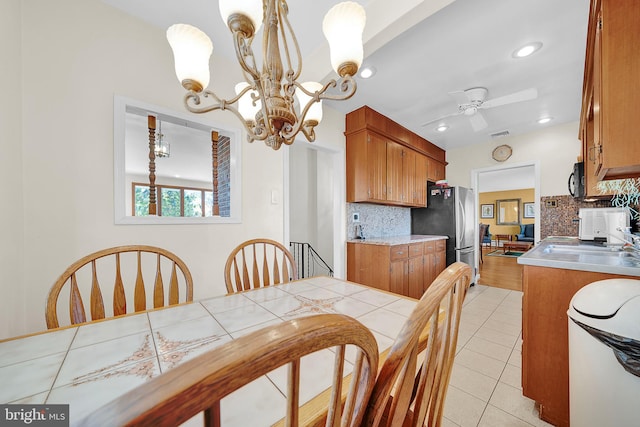 tiled dining area featuring ceiling fan with notable chandelier