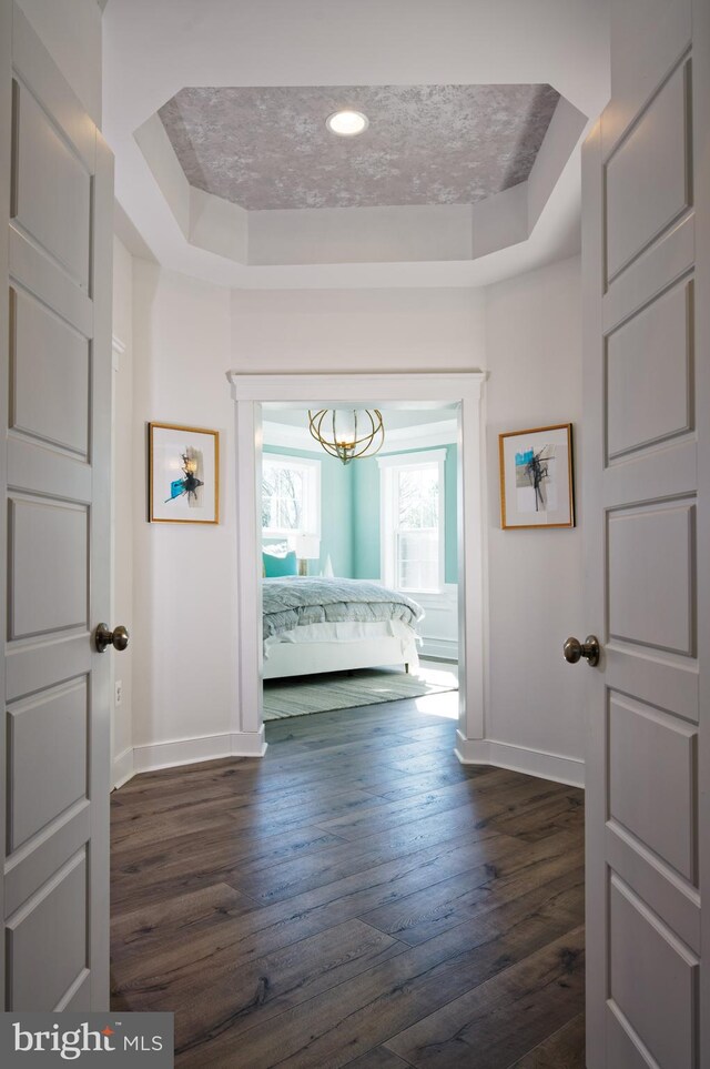 unfurnished bedroom with dark wood-type flooring and a tray ceiling