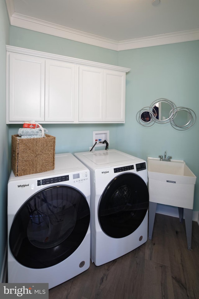 clothes washing area with dark hardwood / wood-style flooring, cabinets, washing machine and clothes dryer, and crown molding