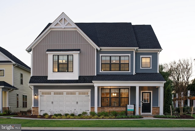 view of front of property featuring a front yard, a porch, and a garage