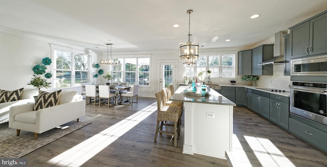 kitchen featuring tasteful backsplash, stainless steel appliances, dark hardwood / wood-style floors, pendant lighting, and wall chimney exhaust hood